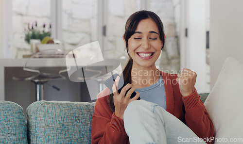 Image of Woman, phone and celebration on sofa, winning and smile with success, profit or online gambling in home. Girl, smartphone and winner with fist to celebrate esport, web casino or achievement on couch