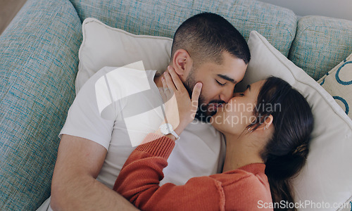 Image of Top view of couple, love and kiss on sofa in living room for romance, intimacy and relax together at home. Young man, woman and kissing partner on couch for happy relationship, quality time and care