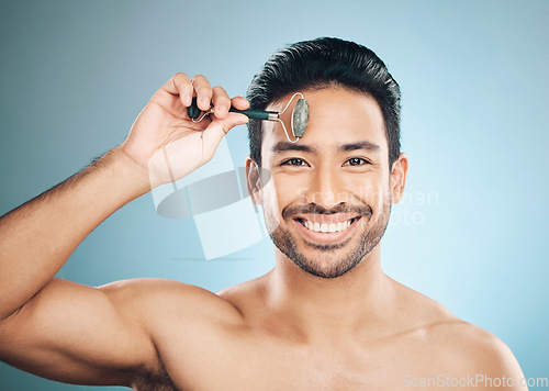 Image of Happy man, portrait or face massage with roller, facial product for healthy skincare on studio background. Relaxing, grooming treatment or male model smiling with dermatology cosmetics for beauty
