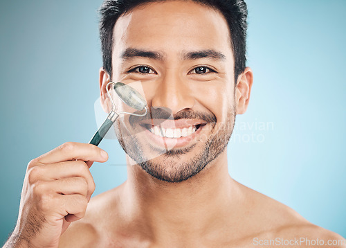 Image of Beauty, portrait or happy man with jade roller, facial product for soft or healthy skincare on studio background. Relaxing, grooming or male model smiling with dermatology cosmetics for face massage