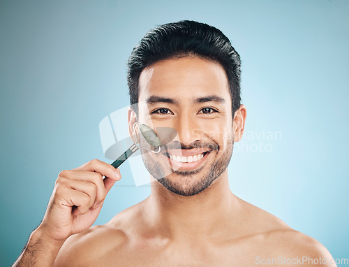 Image of Happy man, portrait or face massage with jade roller, facial product for healthy skincare on studio background. Relaxing, grooming treatment or male model smiling with dermatology cosmetics or beauty