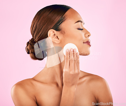 Image of Woman, face and cotton pad in skincare for makeup removal or cosmetics against a pink studio background. Female person or model in relax with cosmetic swab for beauty, cleaning or facial treatment