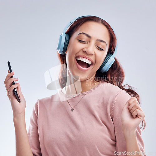 Image of Mobile, headphones or happy girl dancing to music or singing radio songs in studio on white background. Dance, smile or excited woman streaming or listening to audio playlist with cellphone or energy