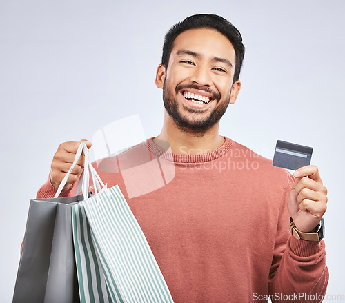 Image of Man is laughing with shopping bag, credit card and happy about discount at boutique isolated on studio background. Humor, funny and male person with payment for purchase, luxury and retail with sale