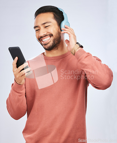 Image of Man, smile and smartphone with headphones, listening to music or podcast isolated on studio background. Male person is enjoying radio streaming, online with wireless technology and playlist on app