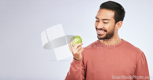 Image of Man, apple and nutrition, health and diet, mockup space and eating isolated on studio background. Male person with smile, green fruit and organic with healthy food, vegan with detox and lose weight