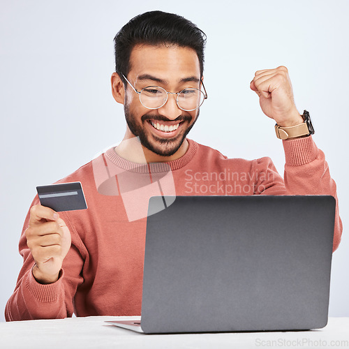 Image of Laptop, credit card and man excited for online shopping, e commerce and payment in studio. Asian male person with technology and hand to celebrate savings win, promotion or sale on a fintech website