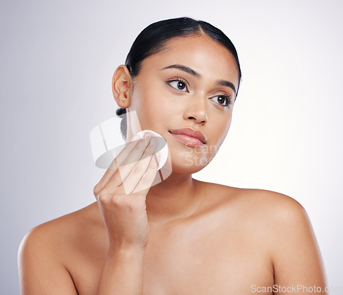 Image of Face, cleaning and cotton on skin of a woman in studio for natural beauty, dermatology or cosmetics. Female person with skincare wipe in hand for glow, healthy and clean facial on a white background