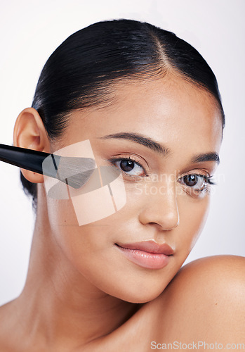 Image of Face, beauty and woman with a makeup brush in studio for skin glow, shine and cosmetics. Portrait of a female model with cosmetic tools in hand for self care and facial powder on a white background