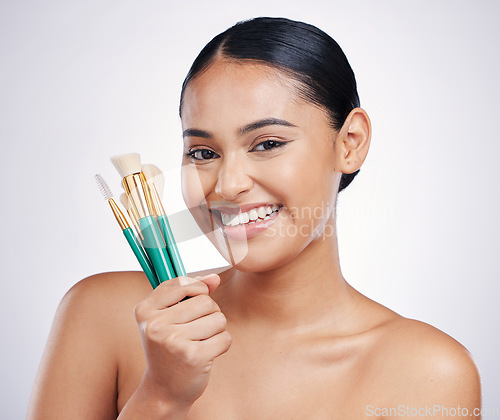 Image of Makeup brushes, face and beauty, woman with smile, foundation and powder isolated on studio background. Female model in portrait, natural cosmetics and skin glow with cosmetic tools and cosmetology