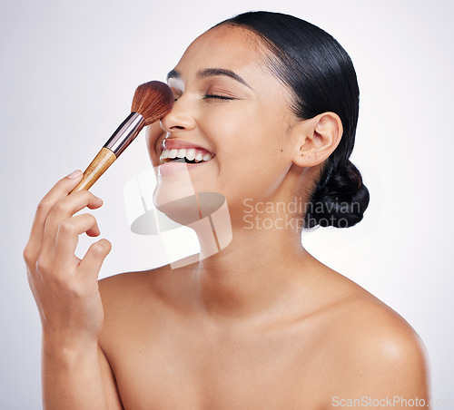 Image of Face, makeup brush and beauty of a woman in studio for skin glow, dermatology and cosmetics. Happy female model laugh with cosmetic tools in hand for self care and facial shine on a white background