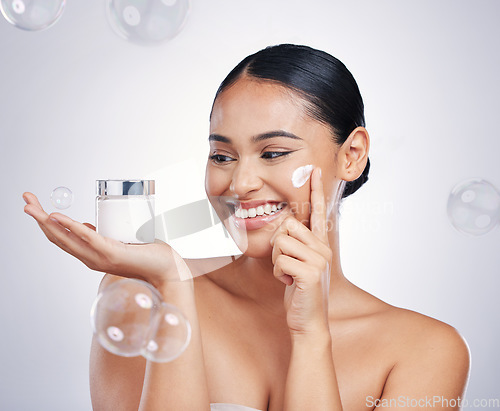 Image of Skin care, face and beauty cream with a woman in studio for glow, dermatology and cosmetics. Female person with a product container in hand with bubbles, health and wellness on a white background
