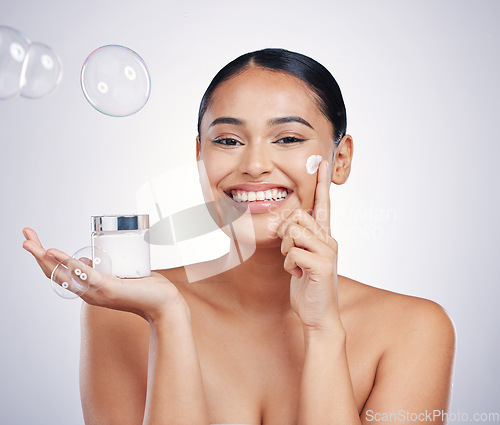 Image of Beauty cream, face and skin of woman in studio for glow, dermatology and cosmetics. Portrait of happy female model with product container in hand with bubbles, skincare and health on white background