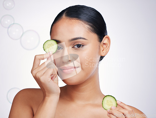 Image of Cucumber, face and beauty of a woman in studio for skin glow, dermatology and cosmetics. Portrait of model person with a vegetable in hand for natural facial, health or wellness on a white background