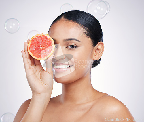 Image of Face, grapefruit and beauty portrait of a woman in studio for glow and natural dermatology. Female person with a fruit in hand and bubbles for facial detox, vitamin c and health on a white background