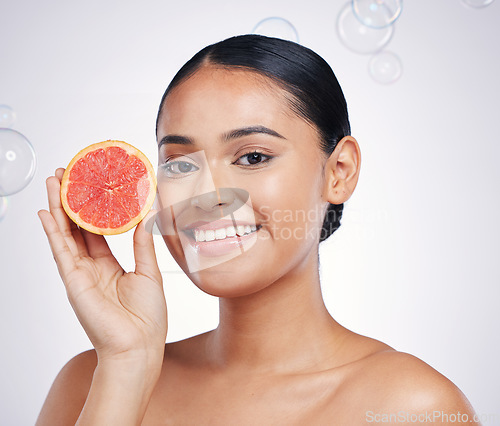 Image of Face, grapefruit and beauty portrait of woman in studio for skin glow, dermatology or natural cosmetics. Model person with fruit and bubbles for detox, healthy diet and skincare on a white background