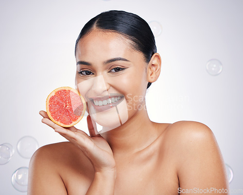 Image of Face, grapefruit and beauty portrait of a woman in studio for skin glow, dermatology or natural cosmetic. Happy person with fruit and bubbles for detox, healthy diet or skincare on a white background