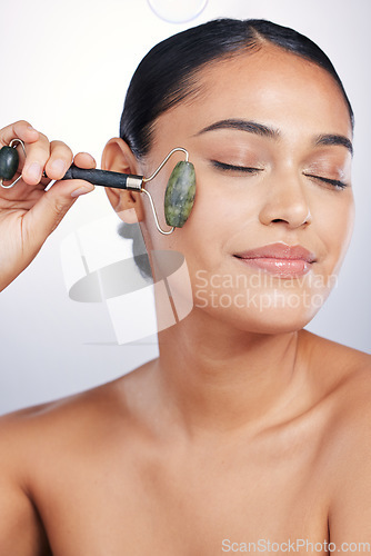 Image of Calm woman, skincare and roller in relax for beauty or cosmetics against a white studio background. Happy female person or model rolling skin with jade stone for healthy wellness or facial treatment