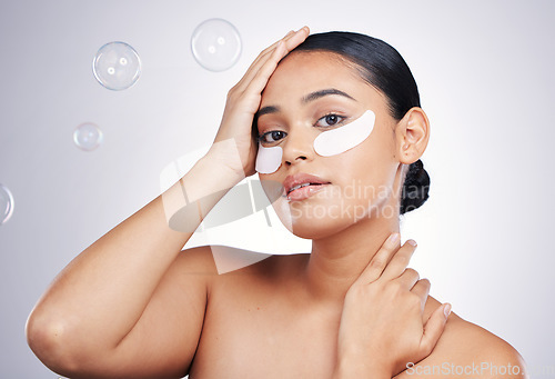 Image of Eye mask, face and a woman in studio for beauty glow, dermatology or natural cosmetics. Portrait of aesthetic model person with a skincare patch and bubbles for facial self care on a white background