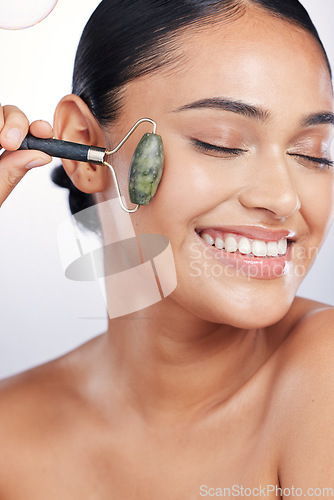 Image of Face roller, skin and a woman in studio for beauty glow, dermatology or natural cosmetics. Happy female model with self care tools for facial massage and skincare results on a white background