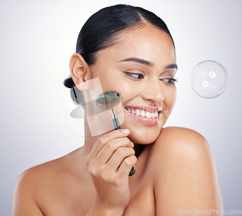 Image of Face roller, skin and a happy woman in studio for beauty glow, dermatology and natural cosmetics. Aesthetic model with tools for facial massage, skincare results and a bubble on white background