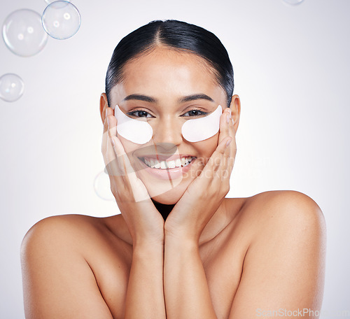 Image of Face, portrait of woman with eye patches and against a studio background with happy smile. Cosmetics or beauty makeup, skincare wellness and young female person with skin treatment against backdrop