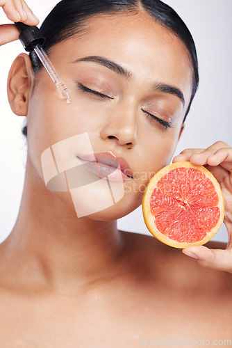 Image of Woman, face and oil with beauty and grapefruit, skincare serum with natural cosmetics isolated on white background. Fruit, female model with pipette and vitamin c for skin with dermatology in studio