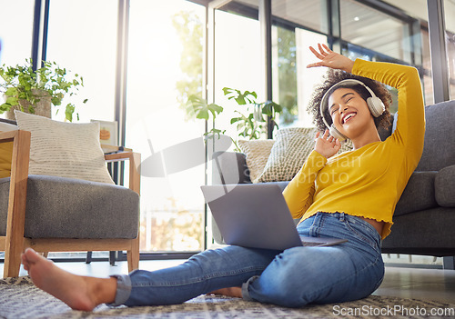 Image of Headphones, computer and home of woman dancing, singing and happy music, podcast streaming or audio. Floor, carpet and young african person on laptop, electronics and web listening in her living room