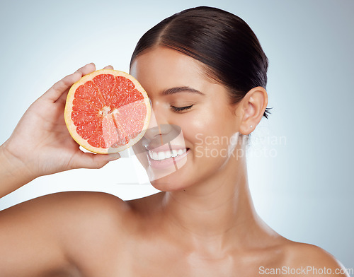 Image of Face smile, skincare and woman with grapefruit in studio isolated on a white background. Vegan, natural and female model with fruit for vitamin c, nutrition or healthy diet, wellness or cosmetics.