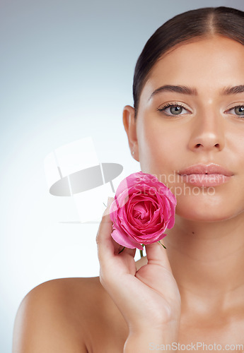 Image of Face, skincare and woman with rose flower in studio isolated on a white background. Portrait, natural plant and serious female model with pink floral for makeup cosmetics, beauty treatment and mockup