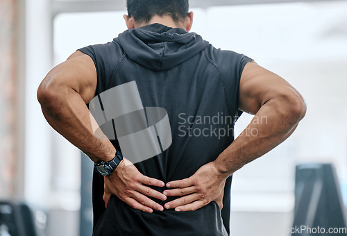 Image of Fitness, gym and man with hands on back pain, medical emergency and workout at sports studio. Exercise, health and wellness, bodybuilder with hand on muscle burnout or ache for massage while training