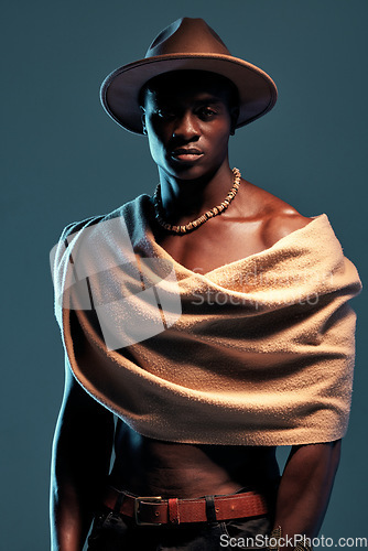Image of Portrait, African man with a shawl and against a blue background. Serious or proud, culture clothing and black male fashion model with a hat pose against a studio backdrop with mockup space.