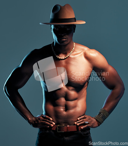 Image of Black man, shirtless and fashion, sexy model with abs and cow boy style with hat isolated on blue background. Dark, shadow and body with muscular male person, pose with six pack and stylish in studio