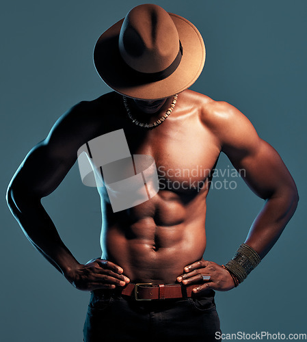 Image of Black man, topless and strong with sexy fashion model, cow boy style with hat isolated on blue background. Dark, shadow and body with muscular male person, pose with six pack and stylish in studio