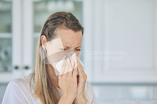 Image of Sick, tissue and woman blowing her nose in the kitchen for a cold, flu or sneeze at her home. Illness, virus and young female person sneezing with allergies, hay fever or covid in her apartment.