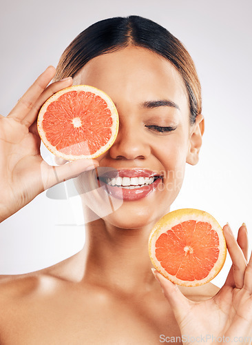 Image of Happy, skincare and woman with grapefruit in studio for natural cosmetic, eco or beauty on grey background. Citrus, facial and female model relax with fruit for skin, detox and vitamin c or collagen