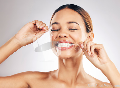 Image of Smile, oral care and woman flossing teeth in studio for hygiene, wellness or fresh breath on grey background. Face, floss and lady relax with mouth, tooth or cleaning for dental or cavity prevention