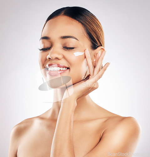 Image of Woman, cream on face and beauty with skincare, smile and moisturizer isolated on studio background. Happy female model apply lotion, dermatology and cosmetic product with skin glow and facial