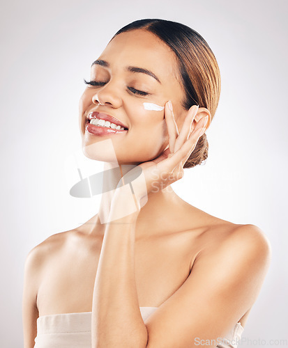 Image of Woman with smile, cream on face and beauty, skincare and moisturizer isolated on studio background. Happy female model apply lotion, dermatology and cosmetic product with skin glow and facial