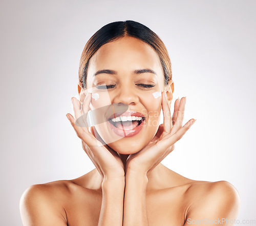 Image of Skincare, beauty and happy woman with face cream in studio for healthy, glowing or anti aging on grey background. Facial, smile and female model excited for dermatology, results and sunscreen lotion