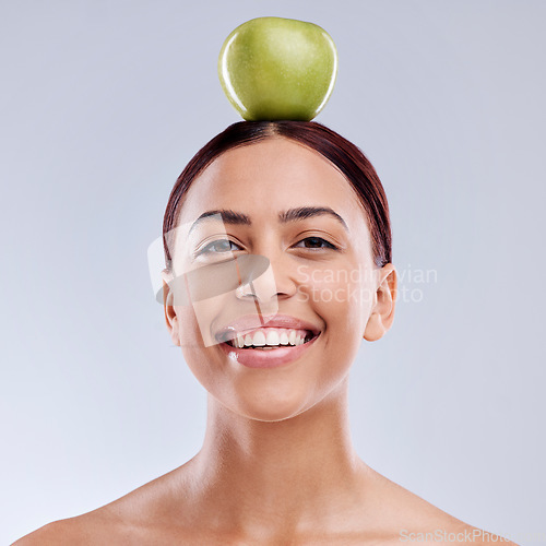 Image of Apple, balance or portrait of happy woman in studio on white background for healthy nutrition or clean diet. Smile, face or beautiful girl with natural organic fruit on head for wellness benefits