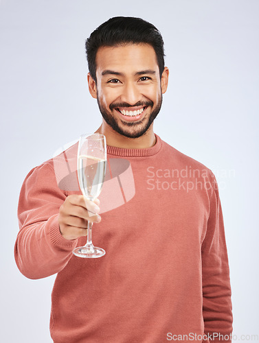 Image of Man with smile in portrait, champagne and cheers with celebration and happiness isolated on studio background. Toast with alcohol drink in glass, happy male model and party, celebrate with drinking