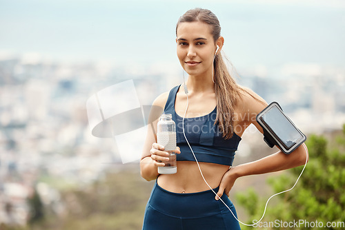 Image of Portrait of woman with earphones, drink water and hiking with fitness app in nature for health and wellness. Music, bottle and girl on mountain with phone for workout with radio streaming or podcast.