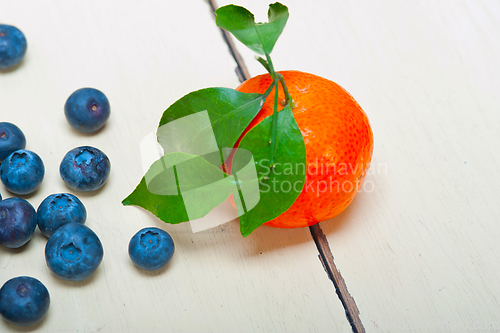 Image of tangerine and blueberry on white table