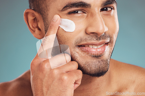 Image of Portrait, facial and cream with a man in studio on a gray background to apply antiaging skincare treatment. Face, beauty or lotion with a young male person applying spf sunscreen indoor for self care