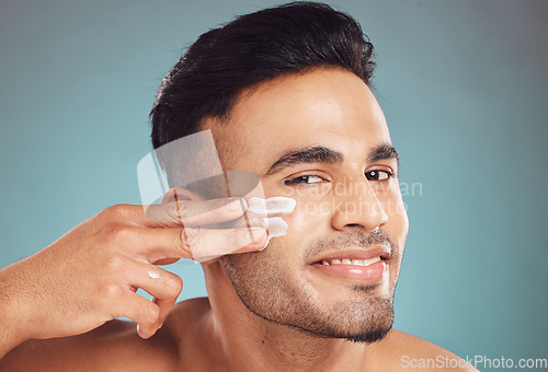 Image of Portrait, beauty and cream with a man on a gray background in studio to apply antiaging face treatment. Facial, skincare and lotion with a young male person indoor for wellness or aesthetic self care