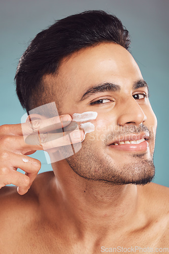Image of Portrait, skin care and cream with a man in studio on a gray background to apply antiaging face treatment. Facial, beauty or lotion with a young male person indoor for wellness or aesthetic self care