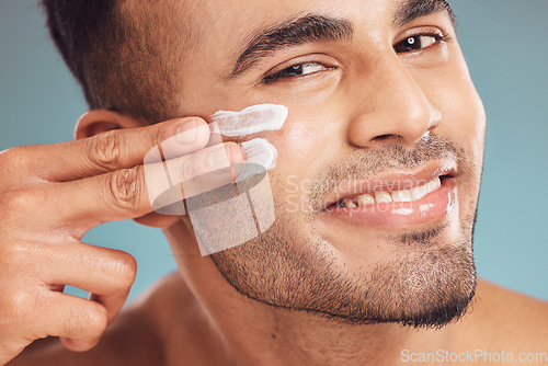 Image of Portrait, beauty and skin cream with a man in studio on a gray background to apply antiaging facial treatment. Face, skincare and lotion with a young person indoor for wellness or aesthetic self care