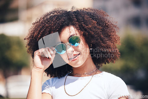 Image of Woman, fashion and sunglasses on face outdoor in city for summer holiday and travel with a smile. Portrait of African person with natural hair or afro and trendy glasses at a park for freedom