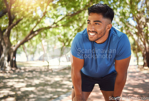 Image of Fitness, break and man or runner outdoor for exercise, training or running at a park. Happy and tired Indian male athlete in nature for a workout, run and rest while thinking of goals or performance